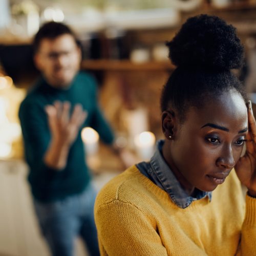 Young black woman feeling worried while having relationship problems with her boyfriend at home.